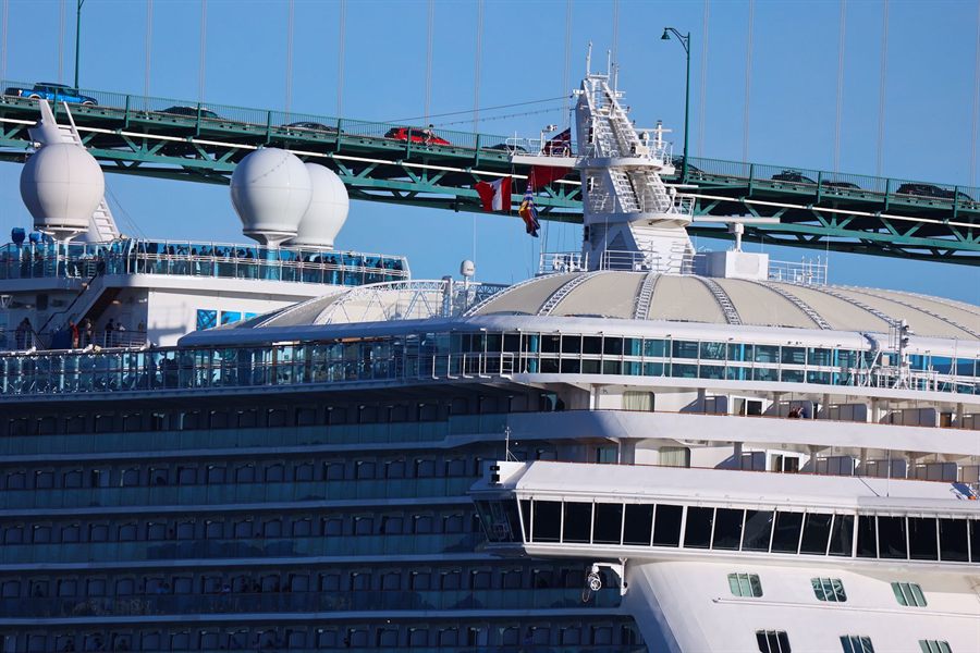 Upper decks of a cruise ship passing beneath a Vancouver bridge