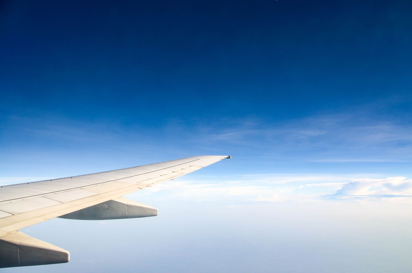 Airplane wing above white clouds and blue sky, the one-way flight home after a repositioning cruise